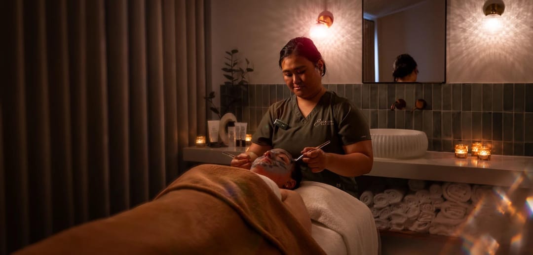 A facial treatment in a candlelit room at Escape Bathhouse